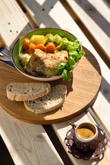Boiled chicken leg and potatoes with zucchini, carrots and herbs served with bread and coffee on a wooden background
