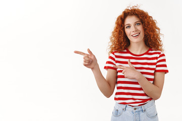 Shall we. Enthusiastic attractive redhead curly woman look curious pointing left index finger smiling happy excited questioned stare asking opinion standing white background intrigued upbeat