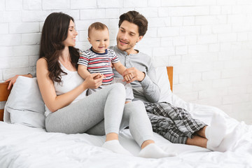 Happy caucasian couple playing with cute baby son at home