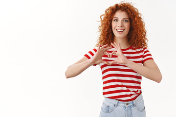 Attractive caucasian redhead woman 25s curly ginger hair show heart sign smiling broadly confess...