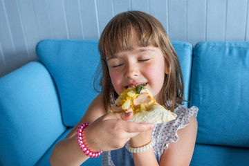 Cute little girl eats pizza. Child has lunch in a cafe, close-up.