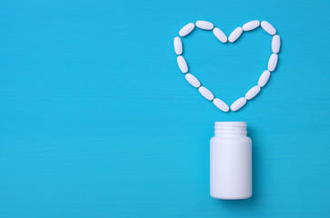 Pills and white bottle on blue background.