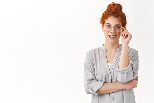 Ambitious good-looking curly redhead woman touching glasses on nose assertive, give professional confident expression, smiling enthusiastic and intrigued, picking new eyewear at opticians store