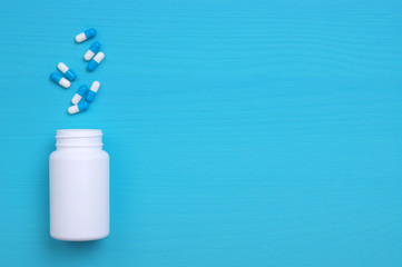 Pills, tablets and bottle on blue background.