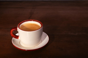 A cup of espresso coffee on a dark wooden background