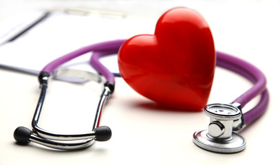 Red heart and a medical stethoscope on desk