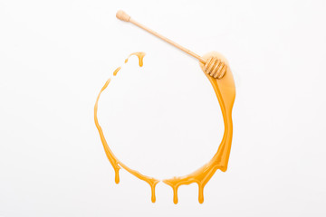 top view of round dripping honey frame with copy space and wooden honey dipper isolated on white