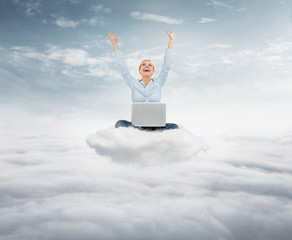 Fototapeta na wymiar Reach the sky concept. Young succesful businesswoman with laptop sitting on the cloud high up in the sky