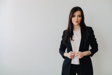 Young attractive emotional girl in business-style clothes on a plain white background in an office or audience