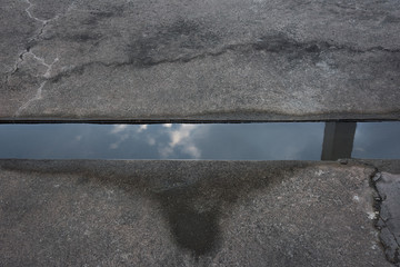 The water in the old concrete pavement is full of water reflecting the beautiful sky.