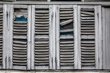 Fototapeta na wymiar Antique windows, worn out by the weather. Gray wooden shutters. Abandoned house.