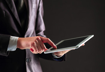 Young businessman working with modern devices, digital tablet PC on a black background