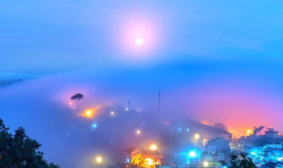 The city sunk in the night fog with bright electric lights in the mist creating a fanciful, impressive scene in Da Lat, Vietnam