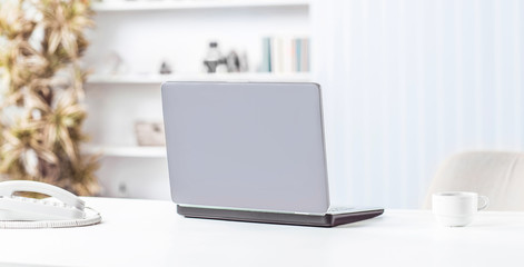 open laptop and Cup of coffee on the table in the nursery.