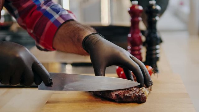 Cutting freshly cooked beef steak on a wooden board
