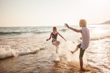 Happy young couple having fun at beach on sunny day