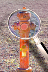 Old red rusty hydrant no longer in use - Concept image seen through a magnifying glass