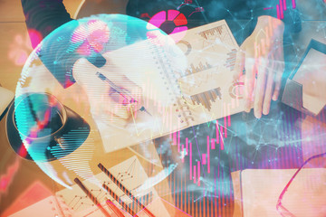 International business hologram over hands taking notes background. Concept of success. Multi exposure