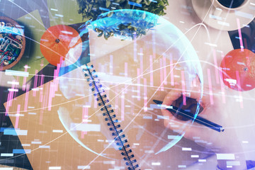 Forex chart hologram on hand taking notes background. Concept of analysis. Double exposure