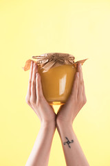 cropped view of woman holding glass jar with honey isolated on yellow