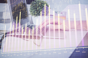 Multi exposure of graph with man typing on computer in office on background. Concept of hard work. Closeup.