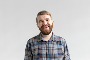 Handsome young bearded man smiling and laughing on white background