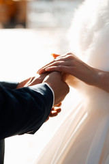 Hands of a wedding couple. Wedding couple holding hands during ceremony. White bridal couple at wedding ceremony outdoors. Vertical color picture.