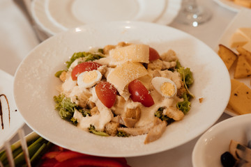 Caesar salad with croutons, quail eggs, cherry tomatoes and  chicken in white plate on celebrate table