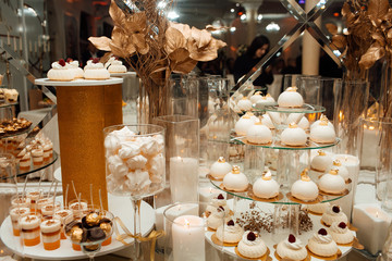 Beautiful modern decoration sweets on table. Delicious wedding reception candy bar dessert table full with cakes and sweets