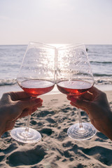 hands with glasses of wine against the sea at sunset