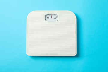 White weigh scales on blue background, top view