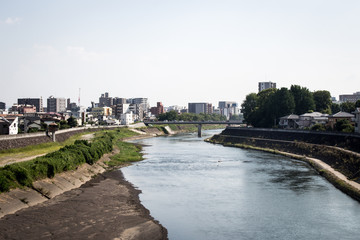Fototapeta na wymiar Cityscape of Kokai and Shirakawa river from Kokai bridge, Kumamoto, Japan. Kokai area is located in the heart of Kumamoto city.