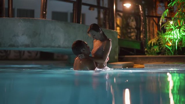 Couple of man and woman swimming in a swimming pool at night. Couple male and female swimming in the pool together at night