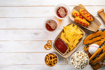 Selection of stadium game foods - nachos, pop corn, pretzels, corn dogs, rustic wood background