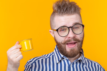 Portrait of a funny self-confident handsome young man in glasses with a beard with a small yellow...