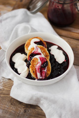 Syrniki or sirniki russian farmers cheese pancakes with raisins, served in a white plate, with jam, sour cream, close up, horizontal, top view, flat lay on a wooden table, copy space