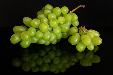 Lot of whole fresh green grape small bunch is aside isolated on black glass