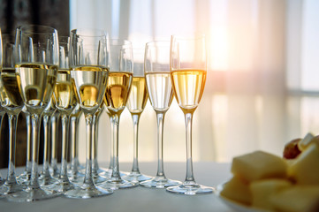 A row of glasses filled with cold champagne lined up, ready to be served. Glasses with Martini on the table - party background. Welcome drink on the wedding ceremony.