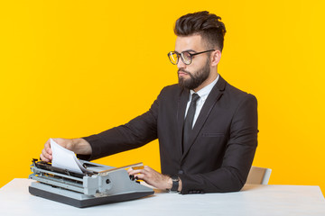 Side view of a young charming male businessman in formal attire and glasses typing on a typewriter text. Concept of business affairs and ideas.