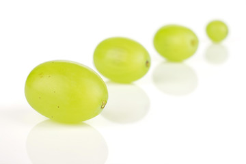 Group of four whole fresh green grape placed diagonally in line isolated on white background