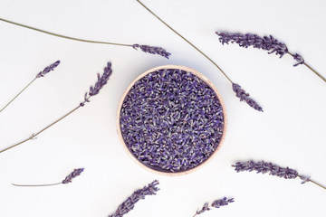 Lavender flowers in wooden plate and branches on white background, toned. Invitation, spa, recipe...