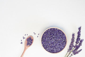 Lavender flowers in wooden plate and spoon, branches on white background, toned. Spa, recipe concept. Top view, close-up, flat lay, copy space, layout design - obrazy, fototapety, plakaty