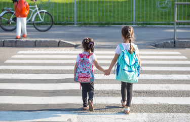 Back to school education concept with girl kids, elementary students, carrying backpacks going to...
