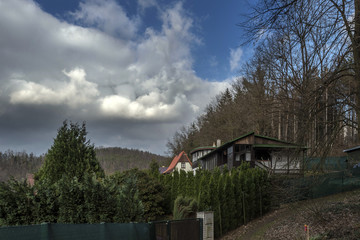 small cottage with red roof in summer forest before thunderstorm