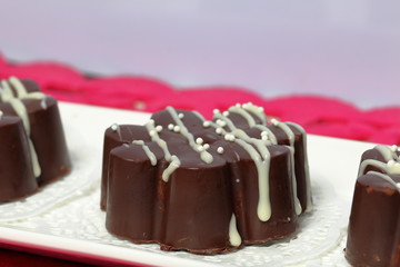Chocolate dessert in the shape of a flower. Dark chocolate coated. Garnished with white chocolate and sprinkles.