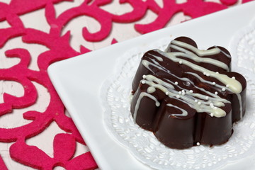 Chocolate dessert in the shape of a flower. Dark chocolate coated. Garnished with white chocolate and sprinkles.