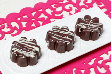 Chocolate dessert in the shape of a flower. Dark chocolate coated. Garnished with white chocolate and sprinkles.