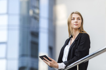 Cheerful blonde with tablet looking away