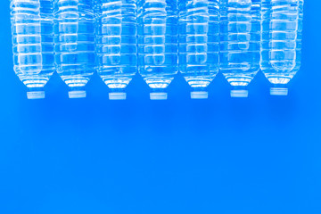 empty plastic bottles for pure water on blue background top view mock up