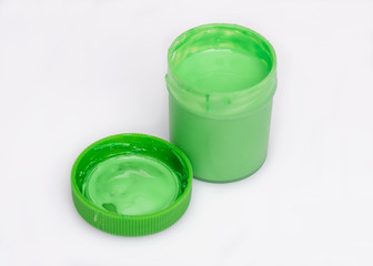 Opened green Gouache jar, on white background with copy space. Cans of different colors gouache paints.